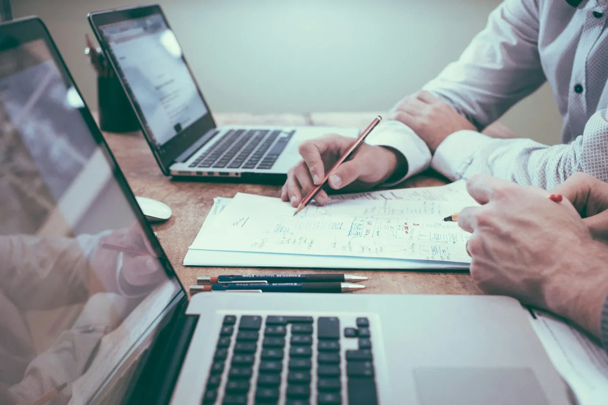 Technical analysis over documents and laptops on a professional desk.